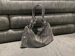 Macro view of crystal rhinestones and decorative knot handle on black evening handbag