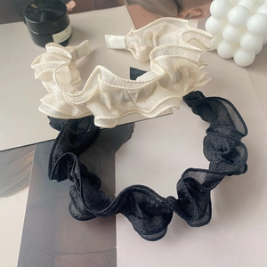 Detail of ruffled chiffon headbands in cream and black featuring pleated layered design
