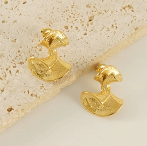 Detailansicht goldene Fächerohrringe mit Hammerschlag-Textur auf Travertin-Stein