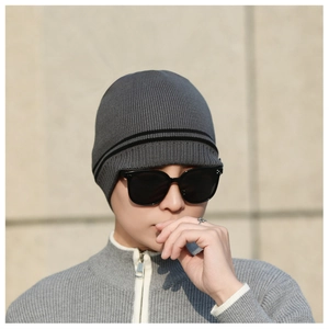 Detail of grey ribbed knit beanie with black stripes worn with sunglasses outdoors