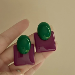 Close-up of retro geometric earrings featuring emerald green oval and deep plum square resin