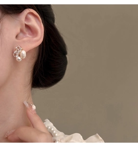 Detailed view of French-style baroque pearl earrings with sparkling zircon on model ear