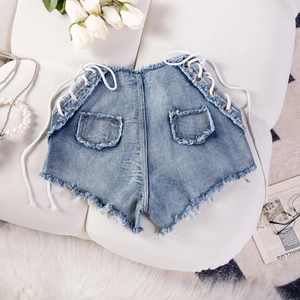 Dettaglio ravvicinato di pantaloncini in denim azzurro con lacci laterali e orli sfrangiati