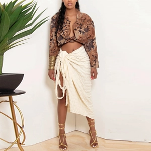 Detailed view of cream-colored wrap skirt featuring a high waist tie and side slit detail