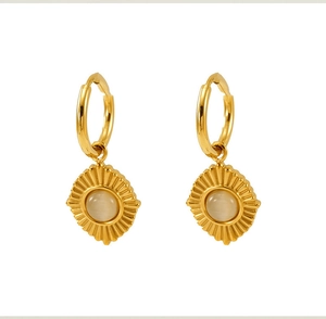 Détail de boucles d'oreilles dorées avec pierre œil de chat et motif soleil sur fond blanc