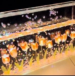 Close-up of DIY tulip night light with warm orange and pink flowers glowing in resin