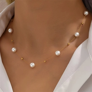 Elegant pearl necklace with gold beads on a model wearing a white shirt collar