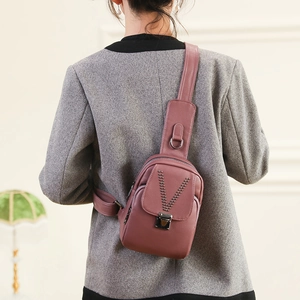 Sac de poitrine pour femme en cuir rose poudré avec clous en V et bandoulière large