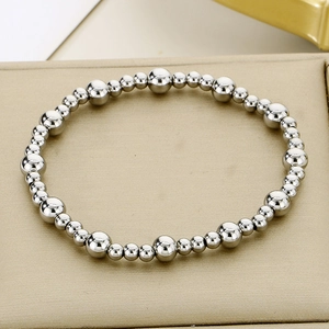 Détail d'un bracelet de perles argentées polies de différentes tailles sur un plateau