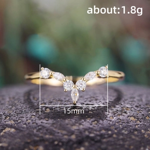 Vergoldeter V-Ring mit Marquise- und runden Zirkonsteinen auf dunklem, strukturiertem Stein