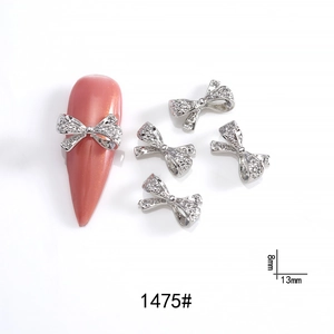 Detail of 8x13mm silver metal bow nail art charm with rhinestones on long pink nail