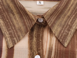 Dettaglio del colletto della camicia con strisce marroni e etichetta della taglia S