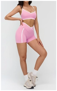 Detailed view of pink yoga set featuring V-neck sports bra and V-waist shorts with contrast piping