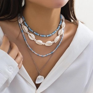Detail of layered beach necklace with starfish, cowrie shells and blue beads on model