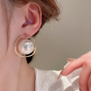 Eleganti orecchini a cerchio dorati con una grande perla bianca su una modella