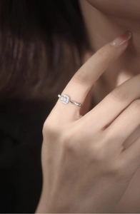 Close-up of a silver chain ring with a large square diamond worn on a finger
