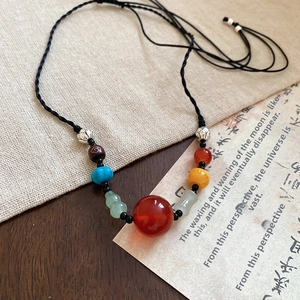 Close-up of ethnic geometric pendant necklace with colorful beads on braided cord