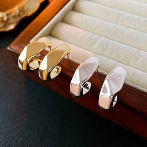 Macro shot of gold and silver irregular C-shaped geometric earrings on a wooden box