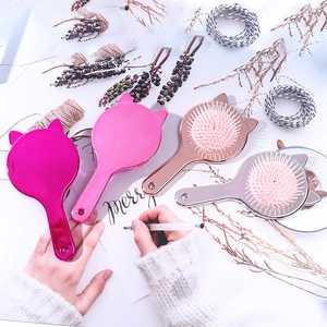 Detail of four metallic cat-ear hairbrushes in rose red, pink, gold, and silver colors