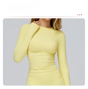 Detail of light yellow yoga long sleeve showing the modest crew neck and slim fit
