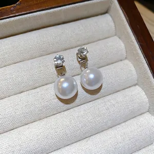 Elegant vintage silver needle pearl earrings with cubic zirconia charms on cream velvet