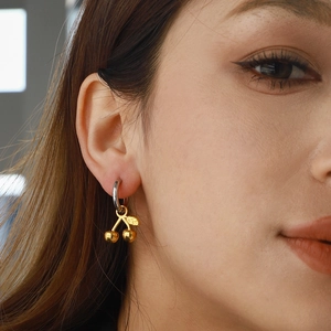 Chic gold cherry earrings in stainless steel on model for a trendy luxury look