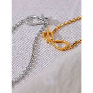 Minimalist gold and silver twist clasp necklaces on a textured fabric background