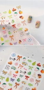Detail von Cartoon-Nagelstickern mit roten Schleifen, Erdbeermustern und 3D-Relief-Textur