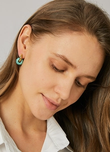 Close-up of bohemian gold hoop earrings with turquoise stone charms worn by a model