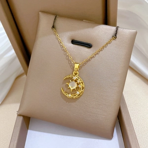 Detail of gold star and moon pendant with shimmering opal stone in a jewelry box