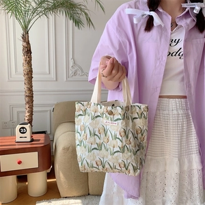 Dettaglio della borsa in tela beige con motivi di tulipani e chiusura a scatto in metallo