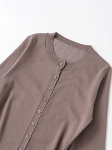 Dettaglio del cardigan in maglia marrone con scollo rotondo e bottoni in tinta