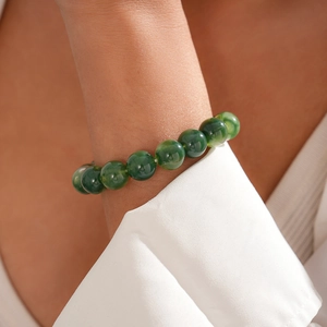 Close-up of green acrylic beaded bracelet on wrist with elegant white shirt detail