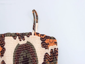 Detail of smocked chest design on beige ethnic print sundress with thin straps