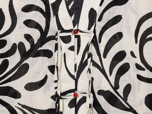 Detailed macro view of white cotton linen fabric with black print and red frog buttons