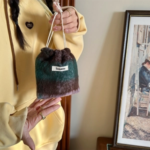 Close-up of striped plush wool drawstring pouch showing soft furry texture and label