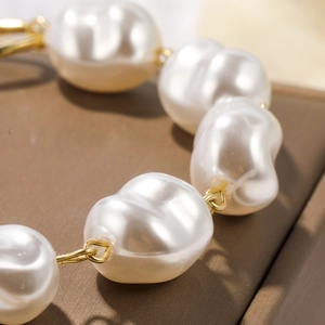 Macro detail of baroque pearls with golden metal links on a dark brown silk background