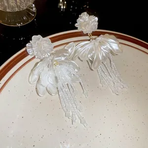 White flower tassel earrings with crystal beads and silver needles on a ceramic plate