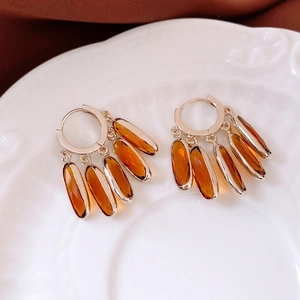 Detailed macro view of vintage oval glass tassel hoop earrings in a light gold finish