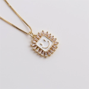 Detail of gold necklace featuring a white smiley pendant surrounded by baguette-cut zircons