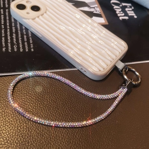 Detail of luxury rhinestone phone strap and white wave-patterned protective case