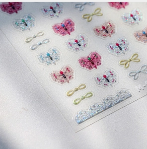 Macro view of 3D gold-stamped bow and butterfly nail stickers with glitter finish