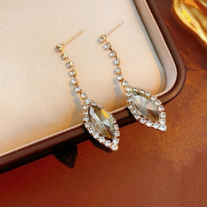 Close-up of gold water-drop tassel earrings with clear crystals in a brown leather box