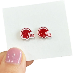 Sparkly red football helmet stud earrings on a card held by a hand with pink nails