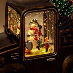 Close-up of a vintage Christmas truck music box with a snowman inside warm lights