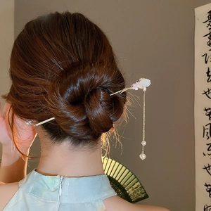 Détail d'épingle à cheveux fleurie avec glands en perles sur modèle dans un cadre chinois