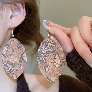 Detailed view of cork leaf earrings with grey butterfly print and gold hooks