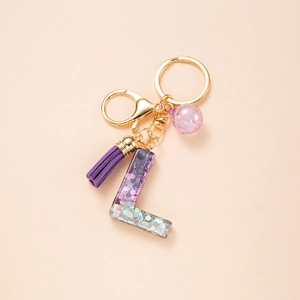 Detail of glitter resin letter L keychain with purple tassel and golden lobster clasp
