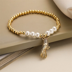 Détail du bracelet pendentif oiseau avec perles dorées, perles blanches et cristaux