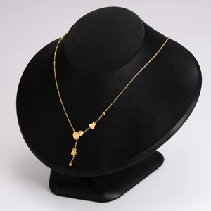 Elegant gold stainless steel necklace with heart and bead charms on a black display stand